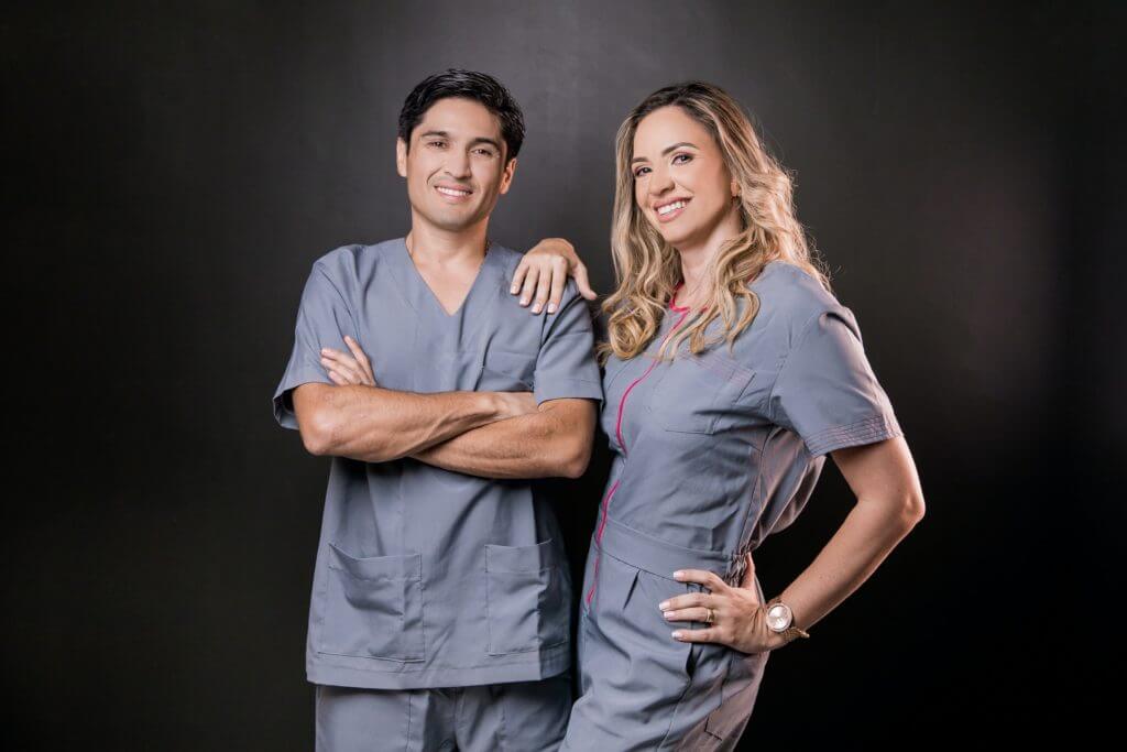 Two dentists wearing scrubs posed and smiling.