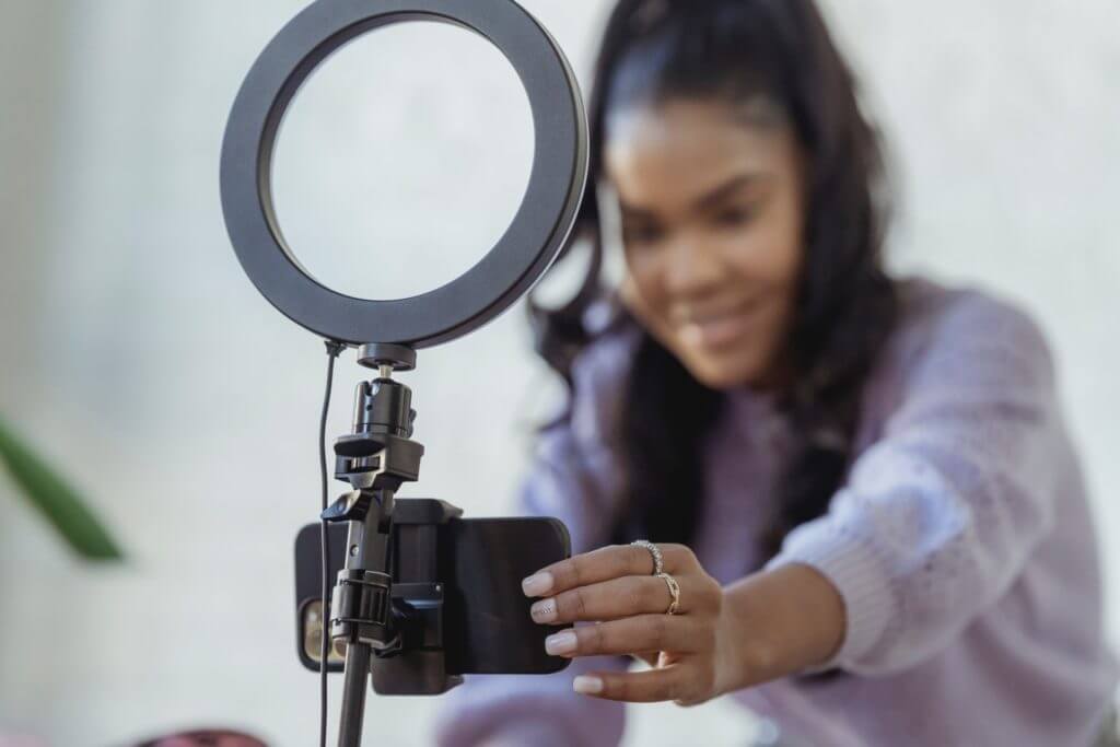 Woman holding iphone with a ring light getting ready to record a video