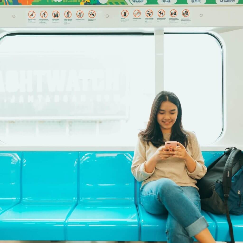 woman sitting on transit looking at phone