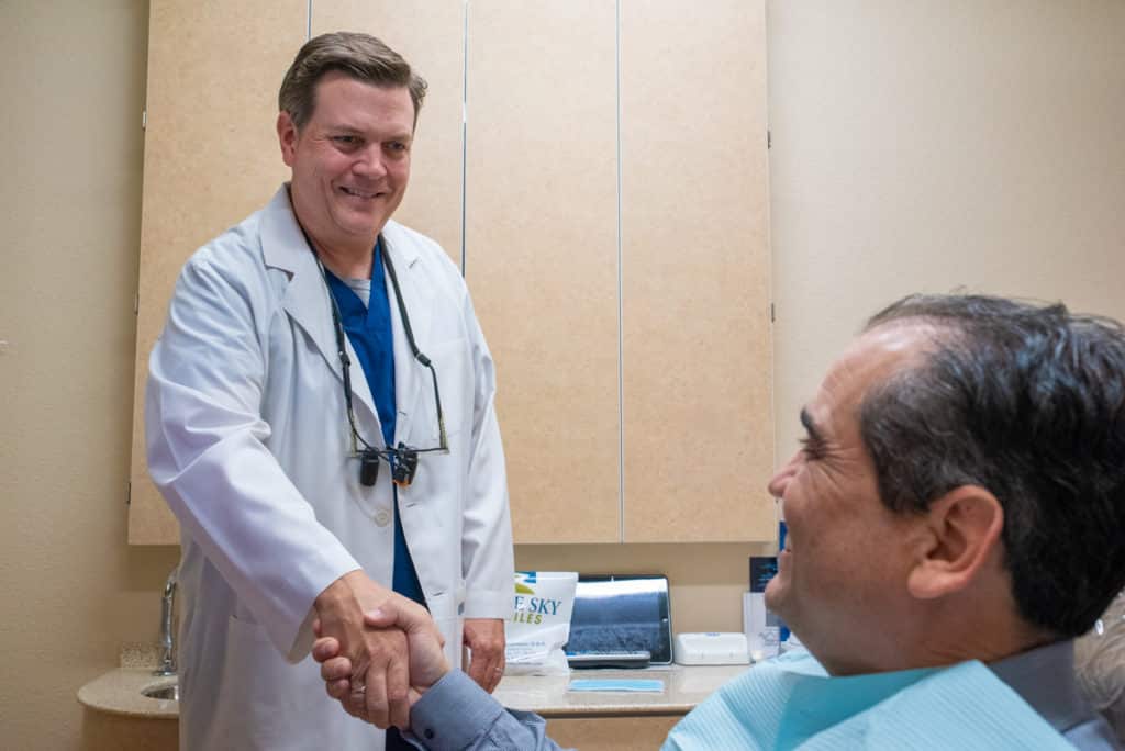 Dentist smiling shaking hands with patient smiling