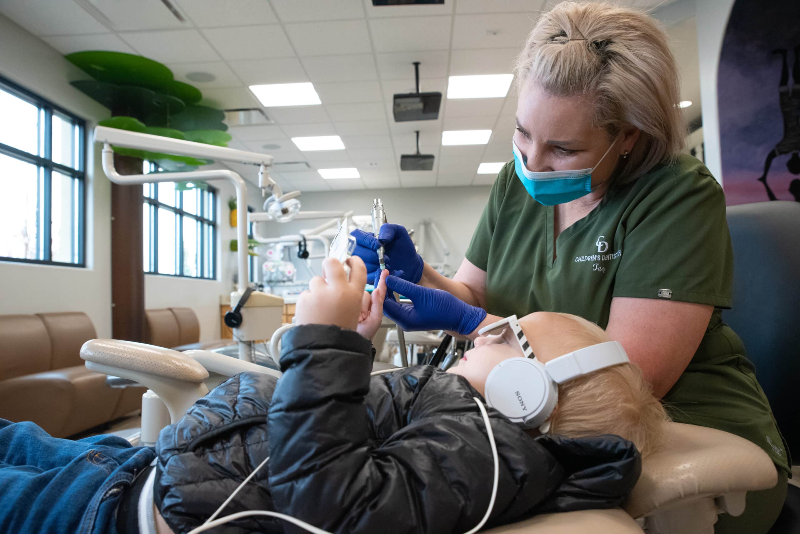 Hygienist showing a dental tool to a child reclined in dental chair