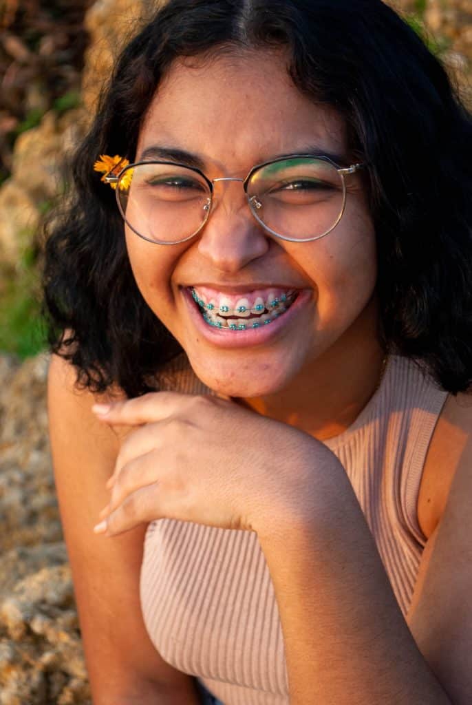 Girl with braces and glasses smiling.