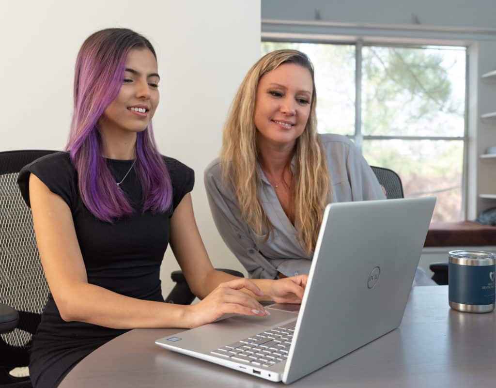 Two pain free dental marketing team members typing on laptop