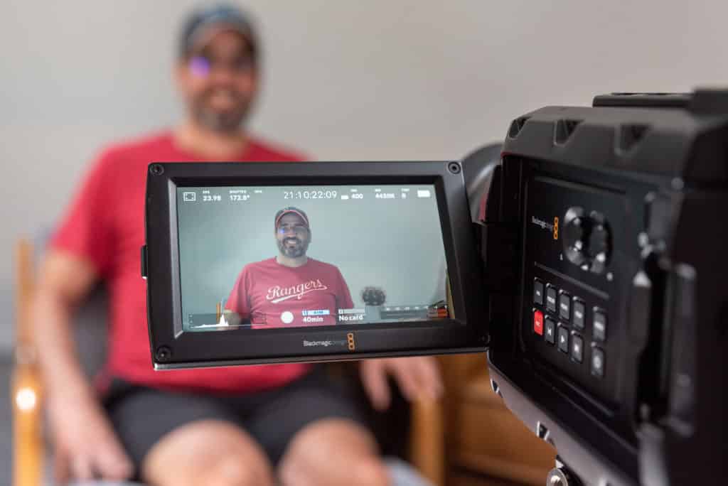 Image of person being interviewed through a video camera screen.