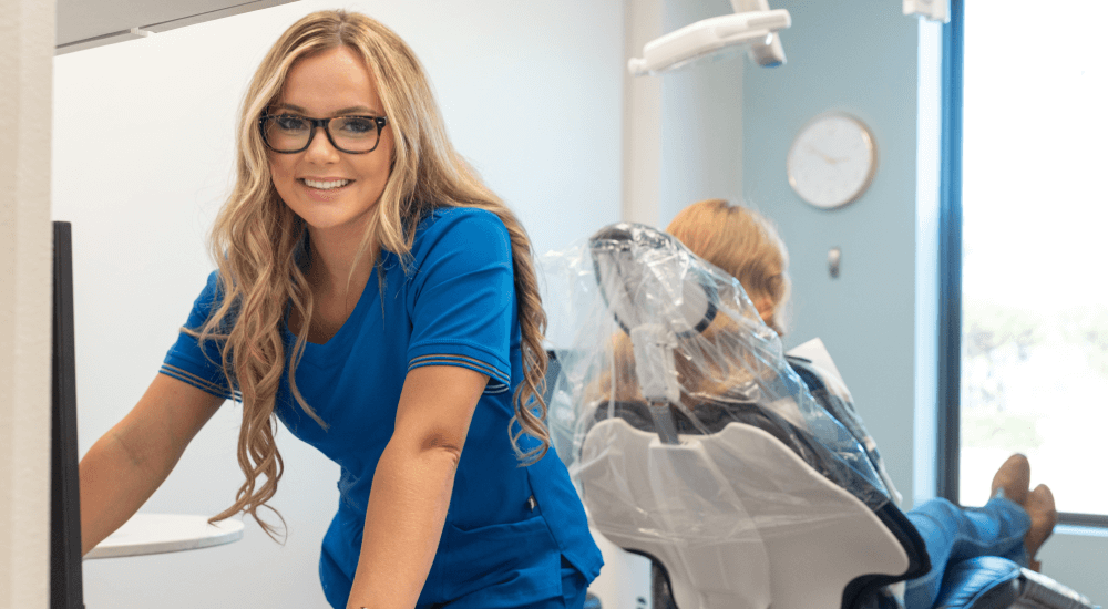 dental hygienist leaning on a desk smiling